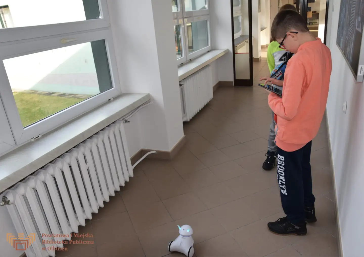 Zdjęcie zrobione w trakcie zajęć GraiBoty - gry planszowe i roboty. Dwójka chłopców koduje na tablecie ruchy robota.